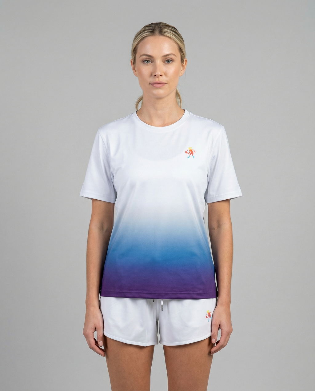 Woman wearing a white to blue gradient t-shirt with a small logo on a gray background