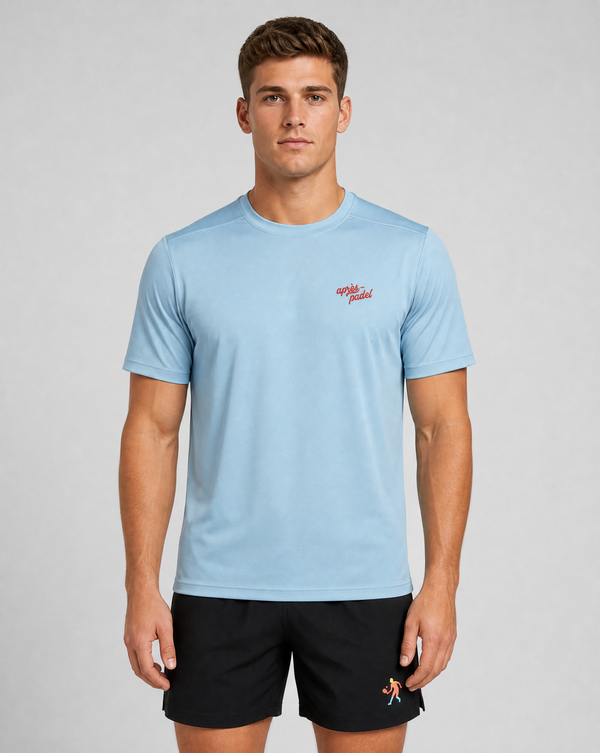 Man wearing a light blue t-shirt with a red logo and black shorts on a gray background