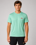Man wearing a light green t-shirt with a small red logo on a gray background