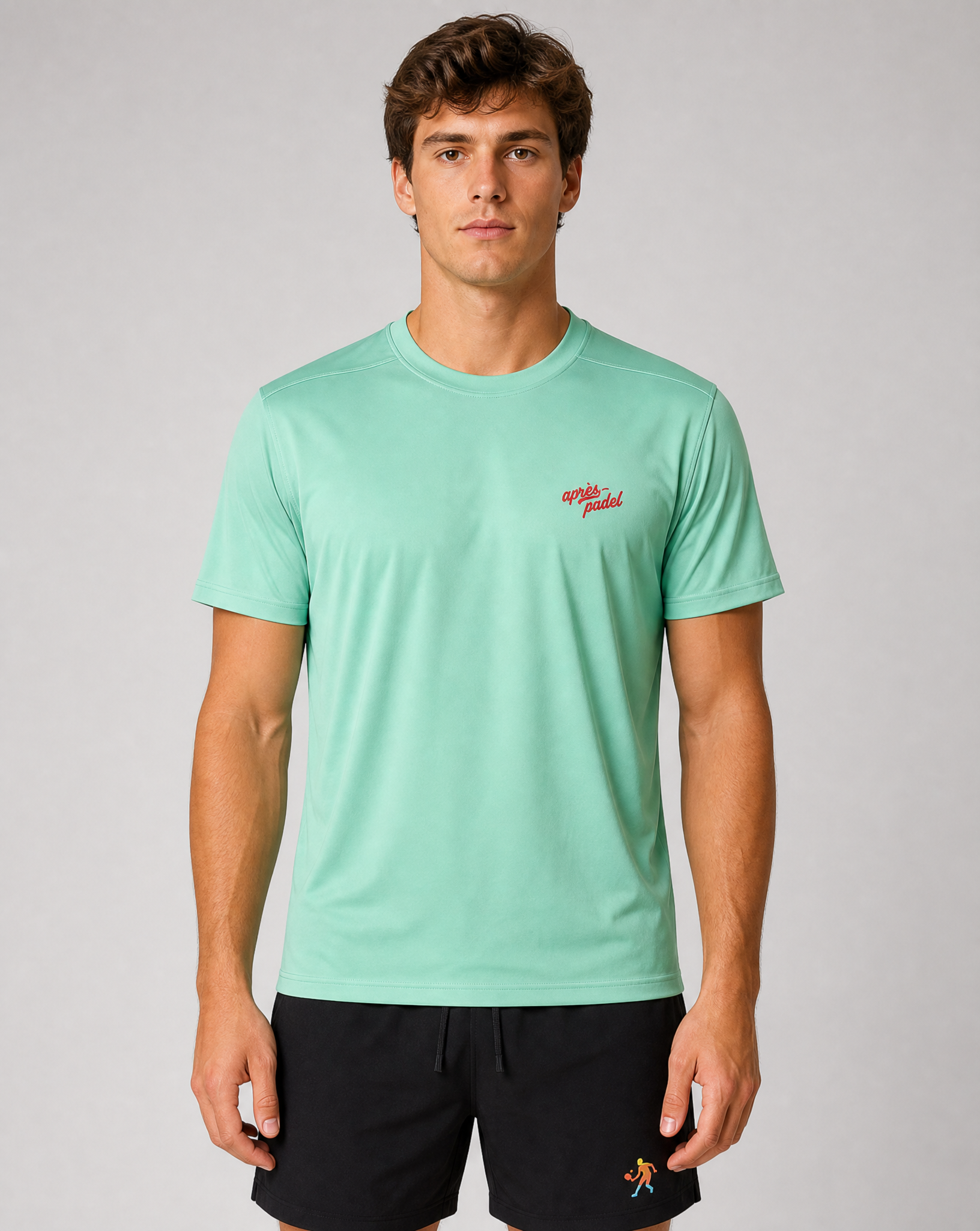 Man wearing a light green t-shirt with a small red logo on a gray background