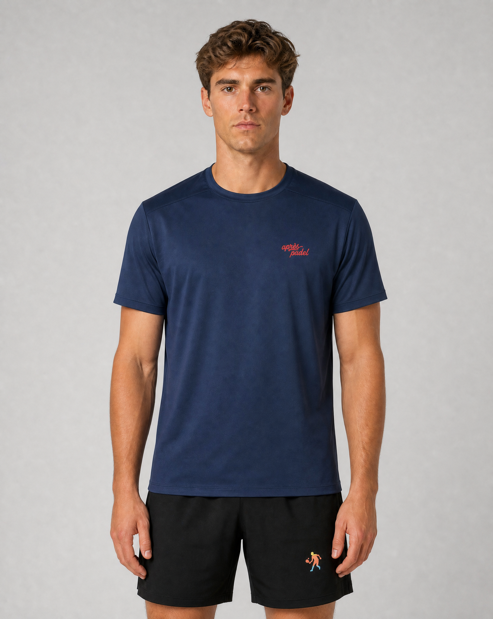 Man wearing a navy blue t-shirt with a red logo on a gray background