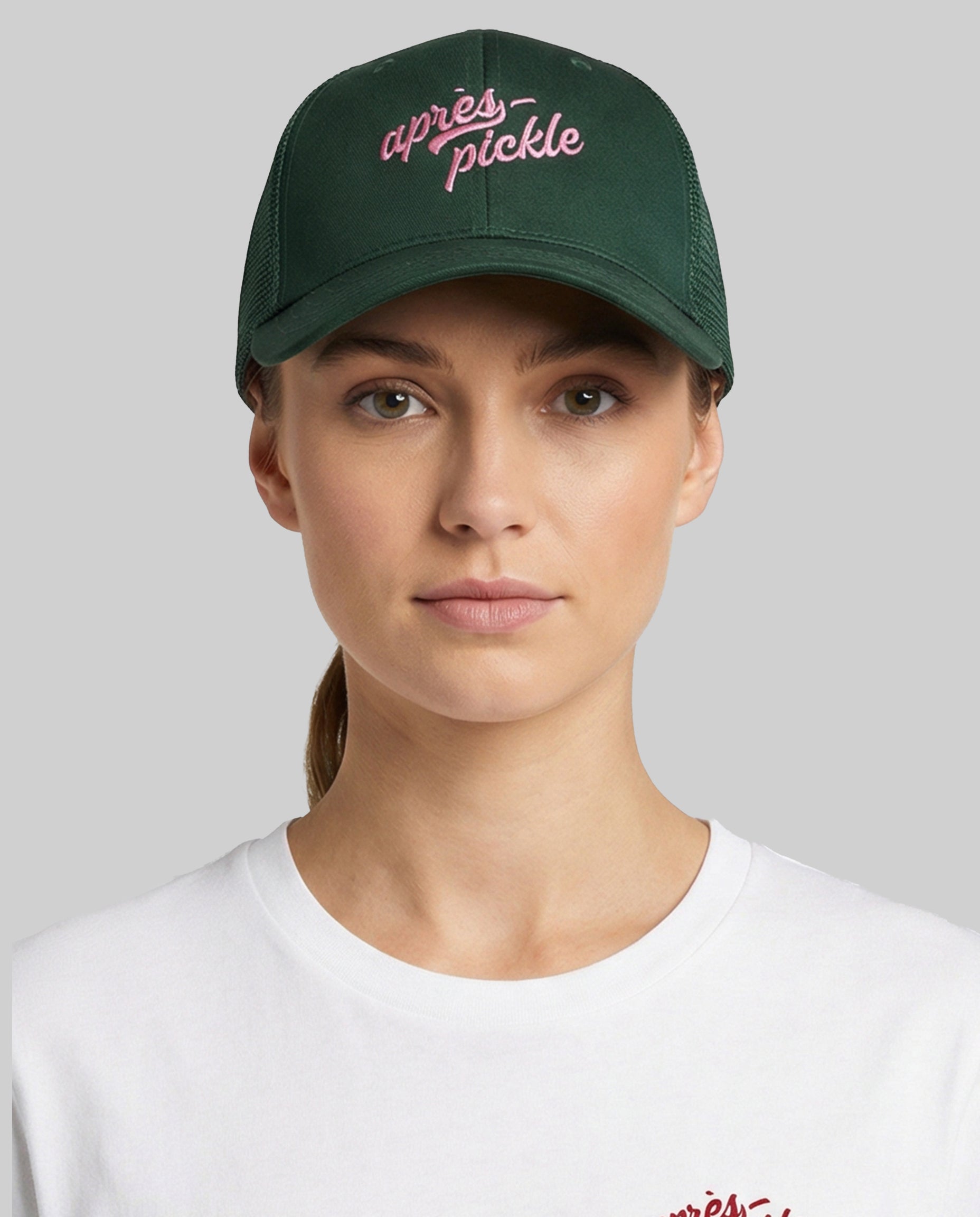 Person wearing a green cap with 'apres pickle' text on a gray background