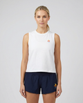 Woman wearing a white sleeveless top and navy shorts with a small logo on a plain background